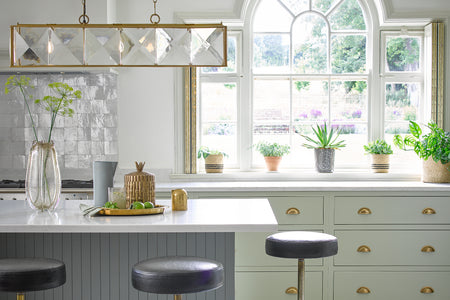 the hunza glass and brass pendant chandelier hanging over a kitchen island.