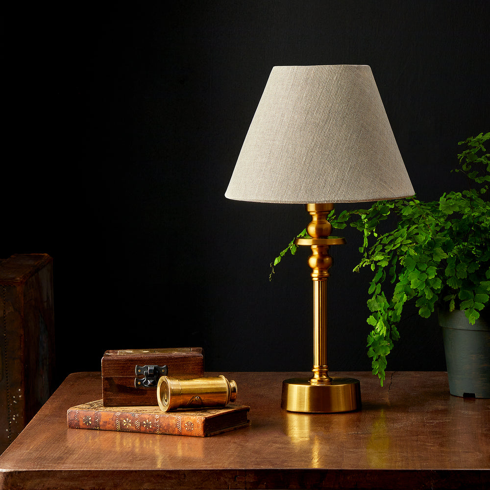 A small sized table lamp with a round base in antique brass